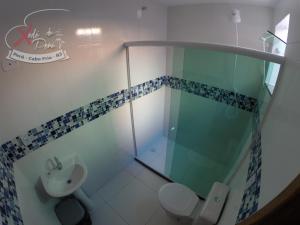 a bathroom with a shower and a toilet and a sink at Xodó do Peró Suítes in Cabo Frio