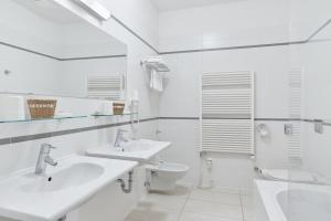 uma casa de banho branca com 2 lavatórios e um WC em Hotel Palatin em Karlovy Vary