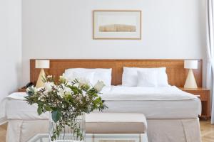 um quarto com uma cama com um vaso de flores sobre uma mesa em Hotel Palatin em Karlovy Vary