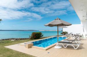 einen Pool mit Sonnenschirm am Meer in der Unterkunft Crystal Villa Miyakojima Sunayama Beach in Miyako-jima