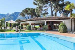 una piscina frente a una casa con montañas en el fondo en Villa Favorita - Parkhotel Delta, en Ascona