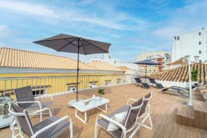 une terrasse avec des chaises, une table et un parasol dans l'établissement Main Street Apartments by Raspberry Cascade, à Faro