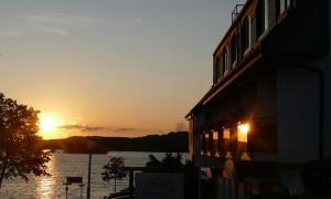 un edificio con la puesta de sol sobre un cuerpo de agua en Hotel Seerose Bad Malente, en Malente