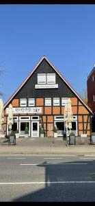 un grand bâtiment noir et blanc avec bancs devant lui dans l'établissement Hotel Stadt Soltau, à Soltau