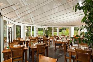 um restaurante com mesas e cadeiras de madeira e janelas em Logis Cottage Hotel em Vandoeuvre-lès-Nancy