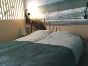 - une chambre avec un lit orné d'une peinture sur l'océan dans l'établissement Fijne Studio aan zee, à Callantsoog