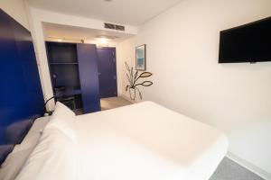 a bedroom with a white bed and a flat screen tv at Hostal Albany in León