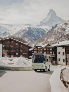 Un piccolo furgone che guida lungo una strada con una montagna di BEAUSiTE Zermatt a Zermatt