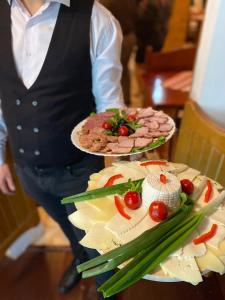 une personne détenant deux assiettes alimentaires sur une table dans l'établissement Pensiunea LUKA Slanic Moldova, à Slănic-Moldova