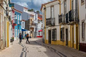 un par de personas caminando por una calle con edificios en Cardume House by Hi Alentejo, en Sines