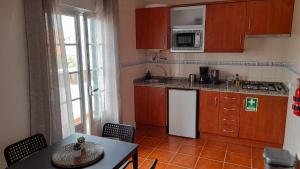 uma cozinha com armários de madeira e uma mesa e uma mesa e cadeiras em Porta Reguengos - Apartamento moderno Alentejo central em Reguengos de Monsaraz