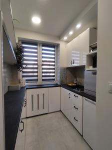 een keuken met witte kasten en een groot raam bij Apartament Wrocław Borowska in Wrocław