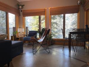 sala de estar con sillas, mesa y ventanas en Blanchard Mountain BnB, en Canmore