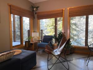 sala de estar con sofá, sillas y ventanas en Blanchard Mountain BnB, en Canmore