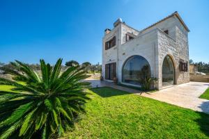 una vista exterior de una casa de piedra con una palmera en FOS residence - ΦΩΣ ,luxury villa, en La Canea