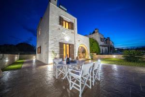 un patio con mesa y sillas frente a un edificio en FOS residence - ΦΩΣ ,luxury villa, en La Canea