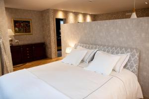 um quarto com uma grande cama branca com almofadas brancas em Seven Luxury Suites em Tirana