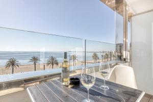 a table with wine glasses on a balcony with the beach at Hotel Marina in Roses