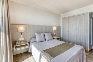 a bedroom with a large bed with two tables and two lamps at Hotel Marina in Roses