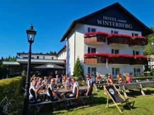 un gruppo di persone seduti su tavoli da picnic di fronte a un hotel di Hotel Winterberg Resort a Winterberg