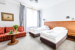 ein Hotelzimmer mit 2 Betten und einem Sofa in der Unterkunft Hotel Pod Złotą Różą in Kielce