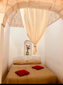 ein Schlafzimmer mit einem Bett mit einem Vorhang und roten Kissen in der Unterkunft CASA ENZA in Ostuni