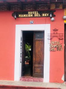 - un bâtiment rouge avec une porte en bois et un panneau dans l'établissement Hotel Mansion Del Rey, à Antigua Guatemala