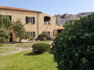 una casa con un cortile con cespugli e alberi di Residence Cala Francese - Case sul mare a La Maddalena