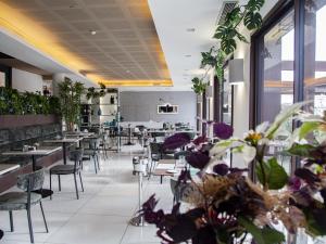 um restaurante com mesas, cadeiras e plantas em Hotel Tiber em Fiumicino