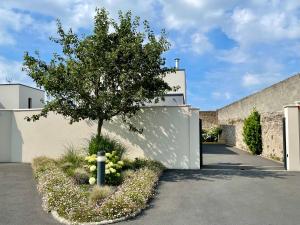 ein Baum vor einem Gebäude mit Auffahrt in der Unterkunft Le Boudoir in Bayeux