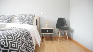 a bedroom with a bed with a chair and a table at Terraço dos Rabujas in Nazaré