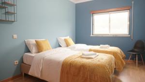 two beds in a room with blue walls and a window at Terraço dos Rabujas in Nazaré