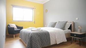 a bedroom with a bed and a chair and a window at Terraço dos Rabujas in Nazaré