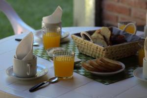 una mesa con tazas de zumo de naranja y una cesta de pan en La Palapa ApartHotel, en Villa General Belgrano