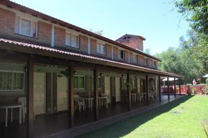 un edificio con mesas y sillas fuera de él en La Palapa ApartHotel, en Villa General Belgrano