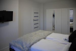 een witte kamer met een bed en een flatscreen-tv bij Apartament Wrocław Borowska in Wrocław