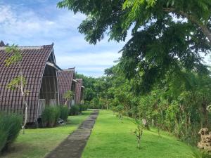 un jardín con un edificio y un patio con césped y árboles en The Ulus Klumpu, en Uluwatu