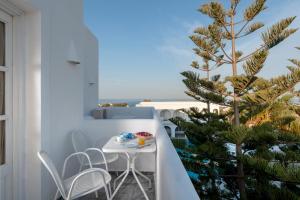 a small table and chairs on a balcony with a tree at Daedalus Hotel in Fira