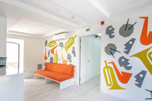 een oranje bank in een kamer met een muur bedekt met borden bij Musical Hostel in Albufeira