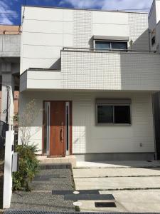 ein weißes Backsteinhaus mit brauner Tür in der Unterkunft Nara Guesthouse Kaede in Nara