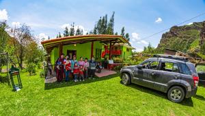 een groep mensen die voor een huis staan met een auto bij Happy Land Valle Sagrado in Urubamba