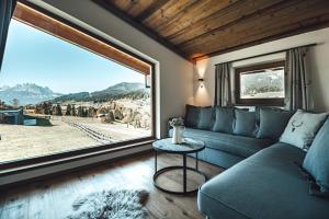 - un salon avec un canapé et une grande fenêtre dans l'établissement Hotel Chalets Grosslehen, à Fieberbrunn