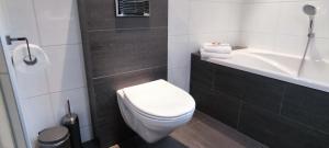 a bathroom with a white toilet and a bath tub at Overbosch in Bilthoven