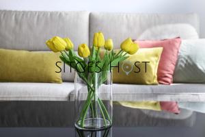 a vase with yellow tulips in front of a couch at A 20 metros de la playa in Sitges