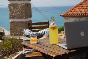 - une table avec un ordinateur portable, une bouteille de jus d'orange et des verres dans l'établissement Chill in Ericeira Surf House, à Ericeira