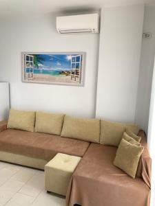 ein Wohnzimmer mit einem Sofa und einem Bild von einem Strand in der Unterkunft Leko’s apt 105 in Himarë