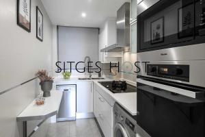 a white kitchen with a stove and a microwave at A 20 metros de la playa in Sitges