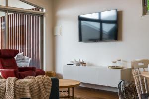 ein Wohnzimmer mit einem Sofa und einem TV an der Wand in der Unterkunft Central Hideaway-close to everything in Warrnambool