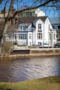 ein großes weißes Haus neben einem Fluss in der Unterkunft Hotell Villa Rönne in Ängelholm