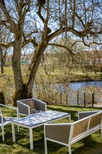 einen Tisch, zwei Stühle, einen Tisch und einen Baum in der Unterkunft Hotell Villa Rönne in Ängelholm